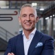 Portrait of a man who stands inside a production building, the background is slightly blurred.