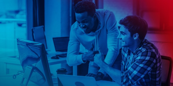 Zwei Personen betrachten einen Computermonitor und geben sich einen Fist-Bump