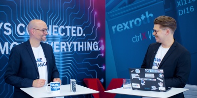 Gospodarz Christian Zentraf i jego gość Benedikt Rüb stoją przy stołach i rozmawiają o ctrlX Configurator, narzędziu konfiguracyjnym rozwiązania automatyzacji ctrlX AUTOMATION.