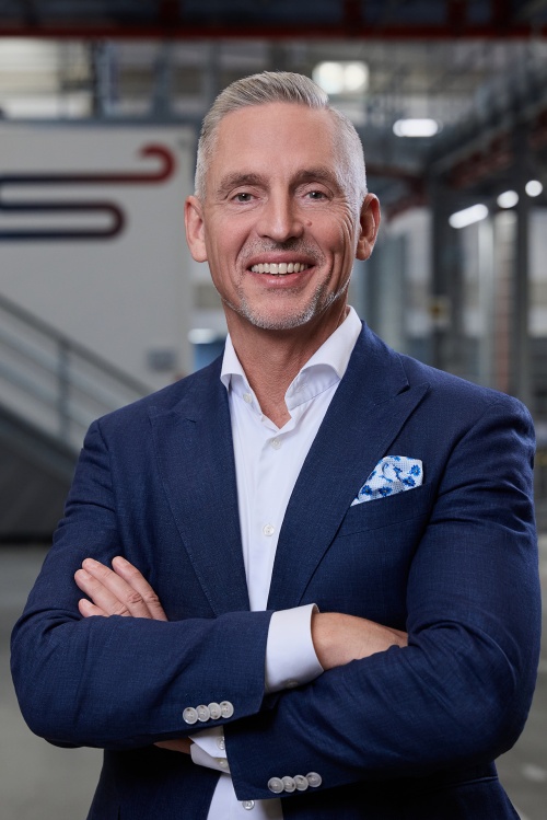 Portrait of a man who stands inside a production building, the background is slightly blurred.