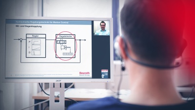 Teilnehmer eines Online-Trainings sitzt vor einem PC und absolviert einen Kurs. Der Trainer ist per Videokonferenz zugeschaltet und erläutert den Lerninhalt.
