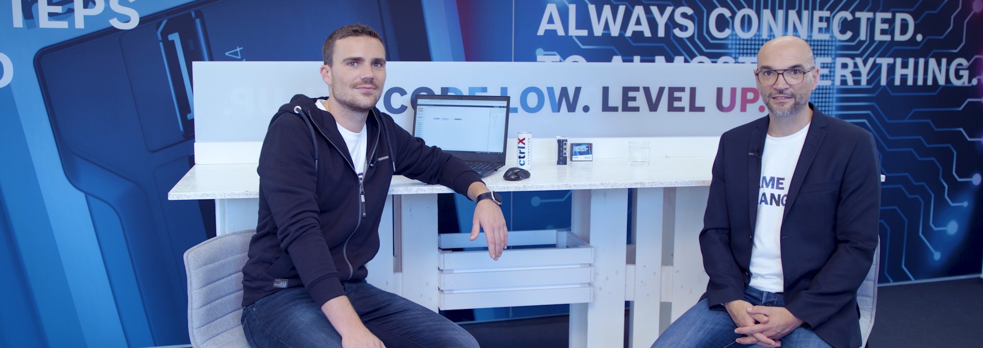 Gospodarz Christian Zentraf i jego gość Johannes Albrecht siedzą przy stole i rozmawiają o standardowych interfejsach, takich jak interfejs REST, rozwiązania automatyzacji ctrlX AUTOMATION.