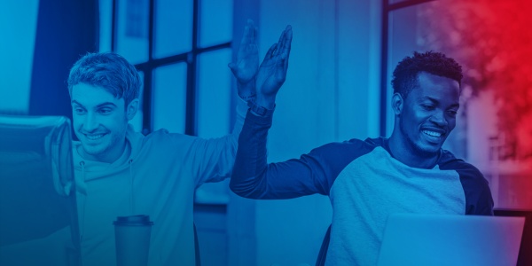 Zwei Personen sitzen am PC und geben sich einen High-Five.