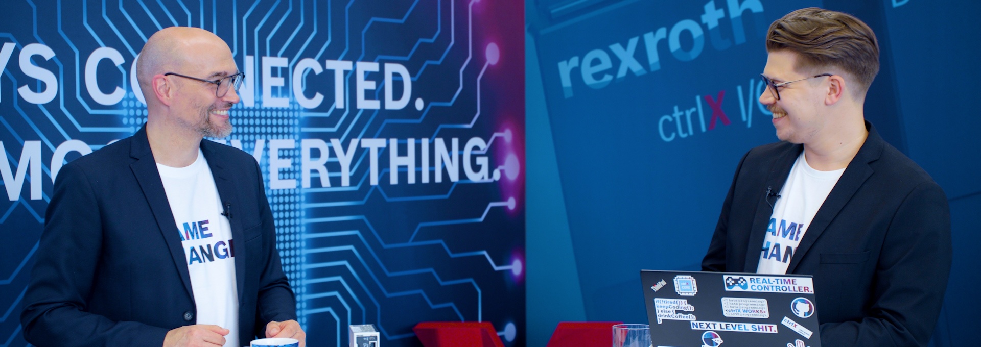 Host Christian Zentraf and his guest Benedikt Rüb stand at meeting tables and talk about ctrlX Configurator, the configuration tool of the automation solution ctrlX AUTOMATION