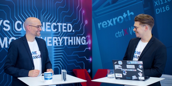 Gastgeber Christian Zentraf und sein Gast Benedikt Rüb stehen an Besprechungstischen und sprechen über den ctrlX Configurator, dem Konfigurationstool der Automatisierungslösung ctrlX AUTOMATION