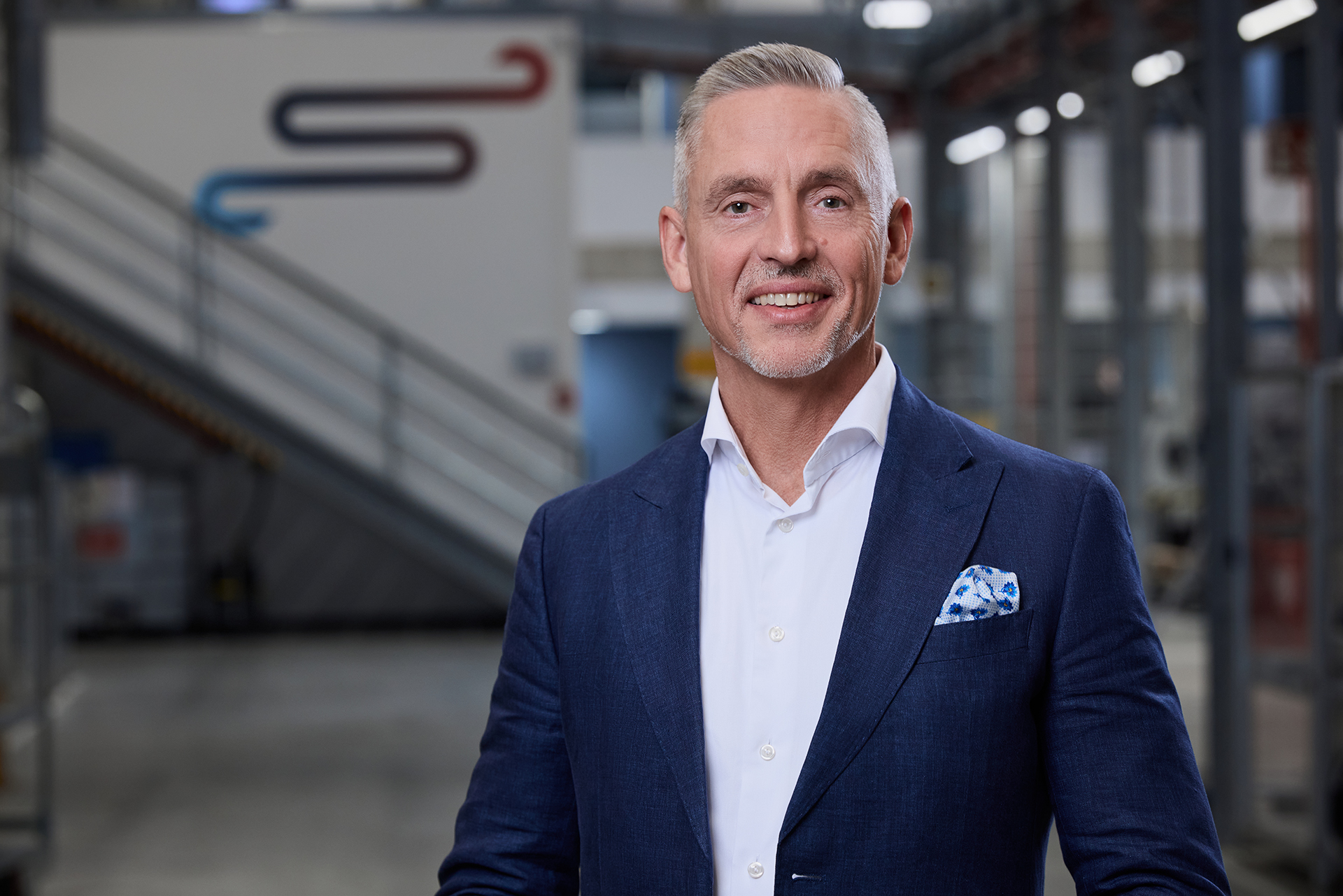 Portrait of a man who stands inside a production building, the background is slightly blurred.
