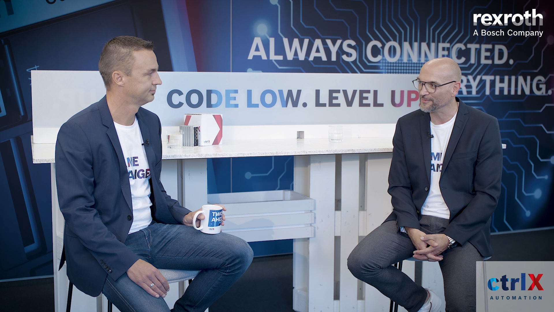 Gospodarz Christian Zentraf i jego gość Holger Schnabel siedzą przy stole i rozmawiają o rozwiązaniu automatyzacji ctrlX AUTOMATION