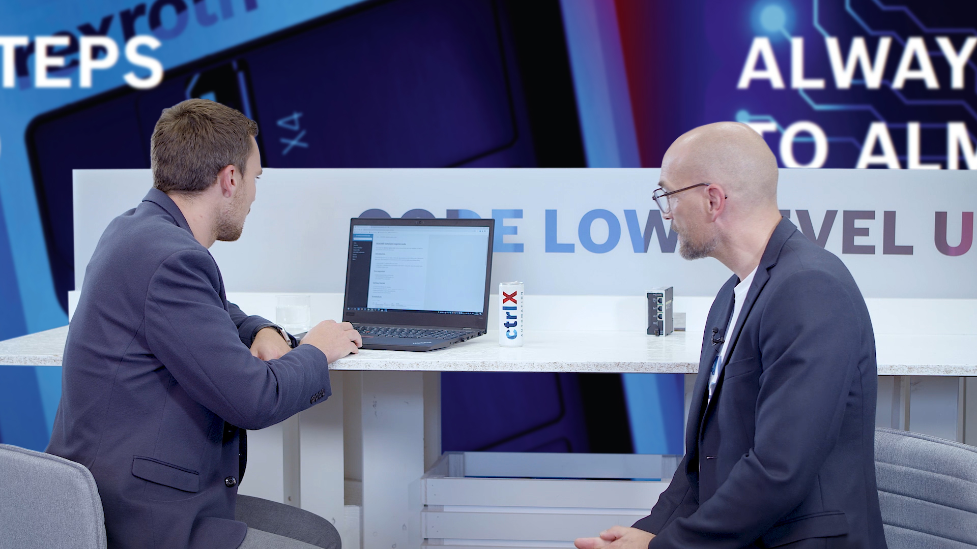 Gastgeber Christian Zentraf und sein Gast Johannes Albrecht sitzen an einem Tisch und sprechen über das Software Development Kit (SDK), zur App-Entwicklung für die Automatisierungslösung ctrlX AUTOMATION