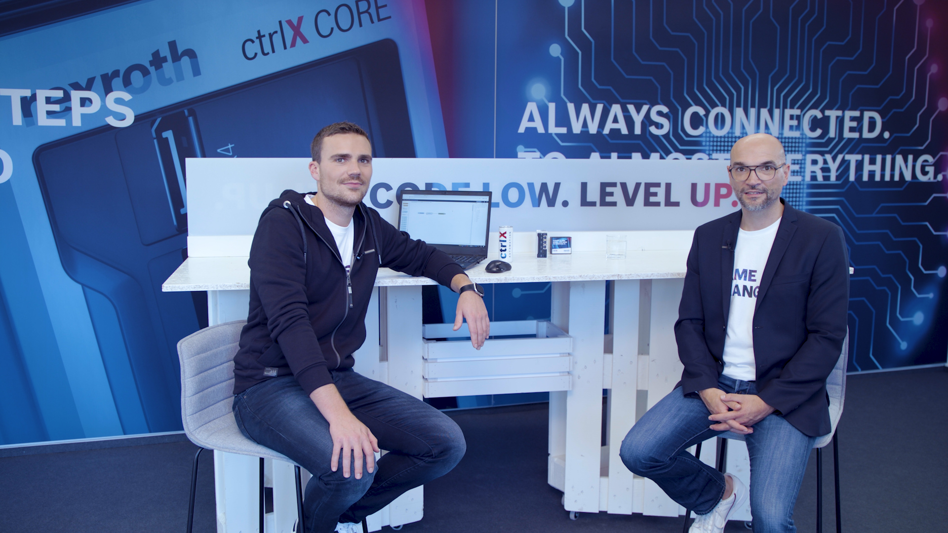 Gospodarz Christian Zentraf i jego gość Johannes Albrecht siedzą przy stole i rozmawiają o standardowych interfejsach, takich jak interfejs REST, rozwiązania automatyzacji ctrlX AUTOMATION.